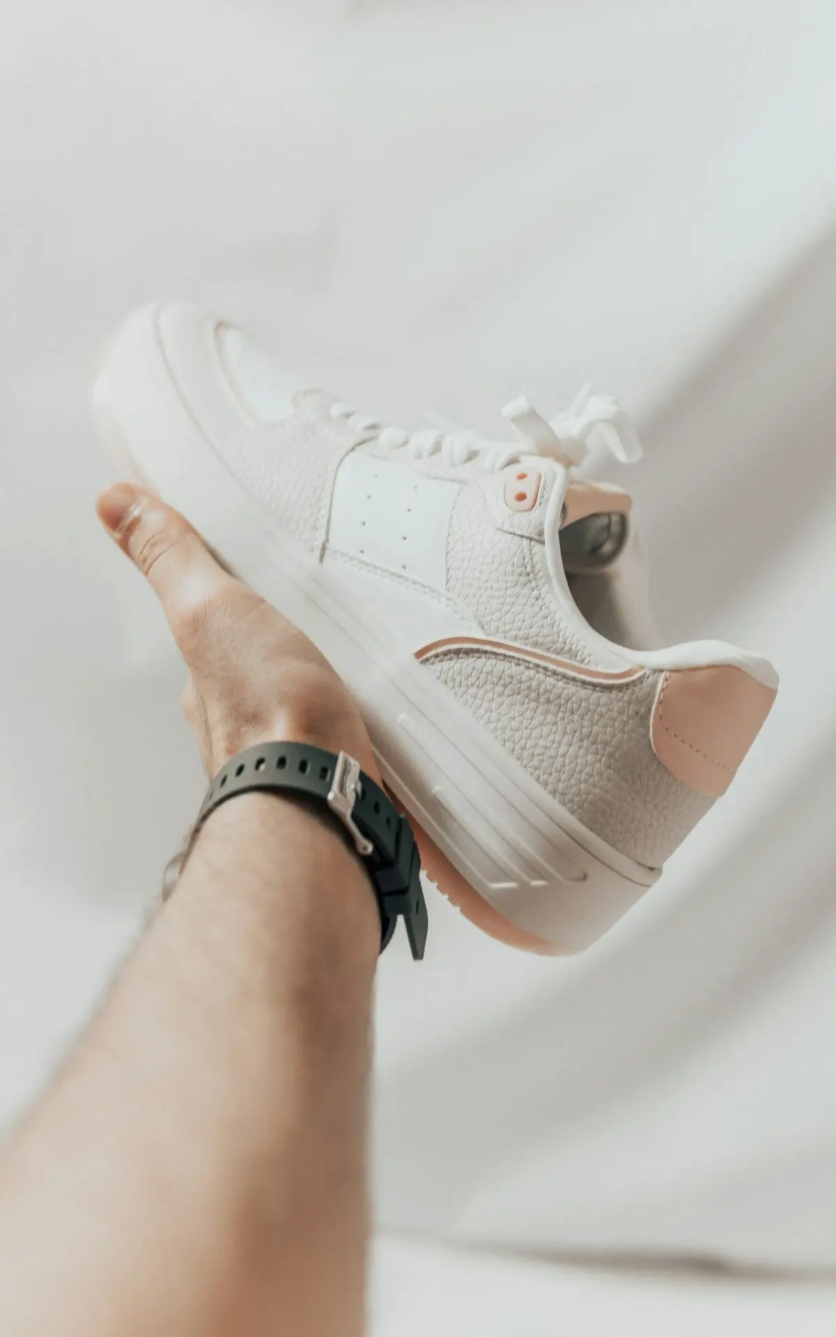 a person holding onto a white tennis shoe